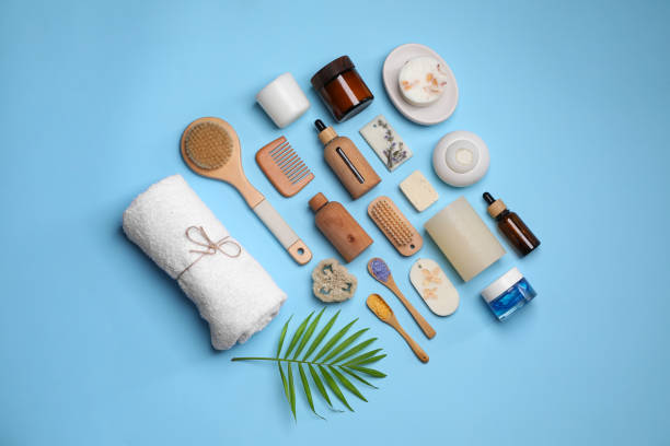 Flat lay composition with different spa products and tropical leaf on light blue background